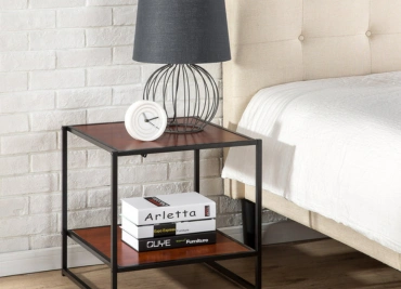 A  bedside table with a black metal frame upper shelves with a lamp, clock & lower shelves with books.