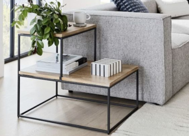 A side table adorned with books & potted plants, showcasing a blend of style & nature in a living space.