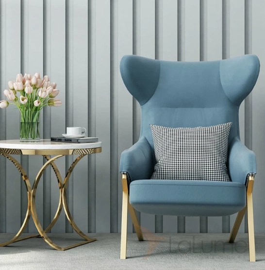 An elegant blue accent chair with gold legs, alongside a charming vase adorned with fresh flowers.